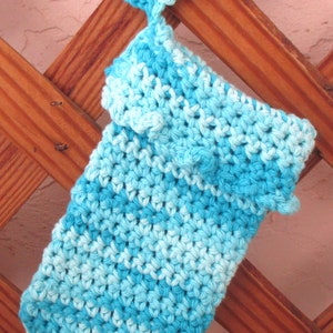 May include: A blue and white crocheted dishcloth with a crocheted loop at the top. The dishcloth is hanging on a wooden trellis.