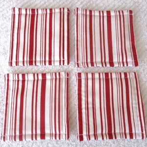 Puede incluir: Conjunto de cuatro posavasos de tela a rayas rojas y blancas. Los posavasos son cuadrados y tienen un dise&ntilde;o acolchado.