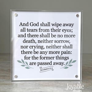 May include: A square, clear acrylic block with a printed white insert. The insert features a Bible verse in black text, with decorative green leaves. The text reads, "And God shall wipe away all tears..." The bottom right corner has the text "Joyable design."