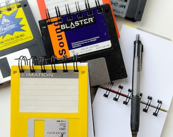 May include: A collection of vintage floppy disks and small notebooks with spiral bindings. The floppy disks are labeled with the text "Sound Blaster", "IMATION", and "MF-2HL".