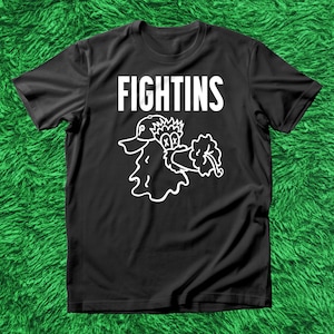 May include: Black t-shirt with the word "FIGHTINS" in bold white letters. Below the text is a white cartoon duck graphic holding a flower. The shirt is made of a soft material.