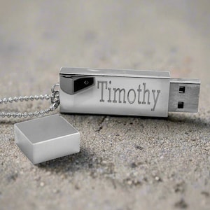 Può includere: Un'unità USB argentata con una catena attaccata. L'unità è incisa con il nome "Timothy".