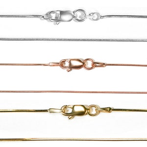 May include: Close-up of four snake chain necklaces in silver, rose gold, and gold tones. Each necklace features a lobster clasp closure. The chains are displayed against a white background, showcasing their delicate design.