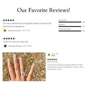 May include: A close-up of a woman's hand wearing a silver ring with a white opal stone. The ring is set in a delicate band with a small heart-shaped accent. The ring is on a finger with white nail polish and a red heart design.