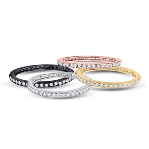 May include: Four eternity bands with a single row of diamonds. The bands are in black, white, rose gold, and yellow gold.