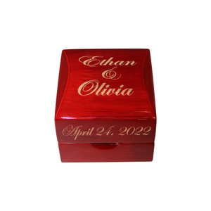 May include: Red wooden ring box with the names Ethan & Olivia and the date April 24, 2022 engraved in gold lettering.