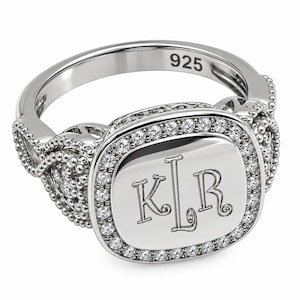 Puede incluir: Un anillo de tono plateado con una cara cuadrada de esquinas redondeadas, grabada con las letras KLR. La cara está bordeada por pequeñas piedras claras y la banda muestra un intrincado trabajo de metal con cuentas. Marcado con 925.