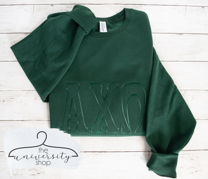 May include: A dark green sweatshirt with the letters "AXO" embroidered in a raised, outlined style.