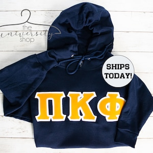 May include: Navy blue hooded sweatshirt with a large yellow and white Greek letter design that reads "ΠΚΦ".