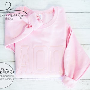 May include: Light pink sweatshirt with tonal embroidery of the letters "AOP".