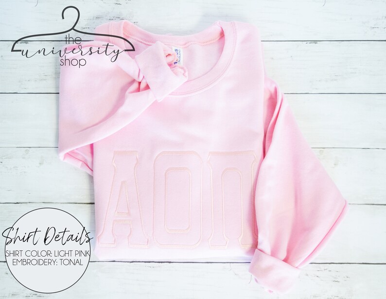 May include: Light pink sweatshirt with tonal embroidery of the letters "AOP".