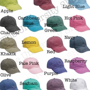 Op de afbeelding: Een verzameling van 18 lege, verstelbare baseballpetten van katoenen twill in verschillende kleuren, waaronder appelgroen, bordeauxrood, caribisch blauw, antraciet, bosgroen, felroze, kaki, citroengeel, lichtblauw, marineblauw, olijfgroen, lichtroze, paars, framboos, rood, koninklijkblauw, zeegroen, wit en wilde pruim.