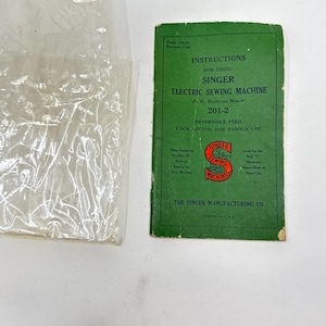May include: Green instruction booklet for a Singer electric sewing machine, model 201-2. The booklet has the text "Instructions for Using Singer Electric Sewing Machine (P.H. Built-on Motor) 201-2 Reversible Feed Lock Stitch, for Family Use" and a Singer Sewing Machines logo.