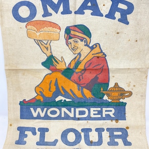May include: Vintage Omar Wonder Flour sack with a cartoon illustration of a man in a turban holding a loaf of bread. The text reads "Omar Wonder Flour" and "Reg. U.S. Patent Office Omaha Flour Mills Co., Omaha."