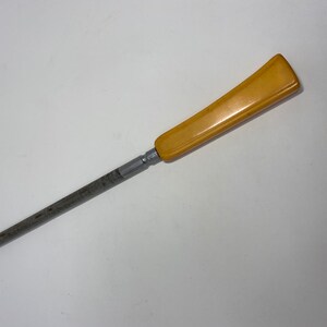 May include: A yellow plastic handle attached to a silver metal knife sharpener.