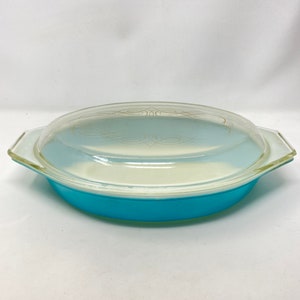 May include: A vintage blue Pyrex baking dish with a glass lid. The dish has a gold swirl design on the lid.
