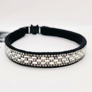May include: A black headband with a row of clear rhinestones. The headband is made of a soft, stretchy material and is perfect for adding a touch of sparkle to any outfit.