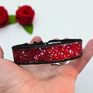 May include: A red crystal choker necklace with a black velvet band. The necklace is made with small, faceted crystals that sparkle in the light.