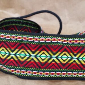 May include: A black woven belt with a colorful geometric pattern in red, yellow, green, and white. The belt has a long black cord that can be tied to adjust the fit.