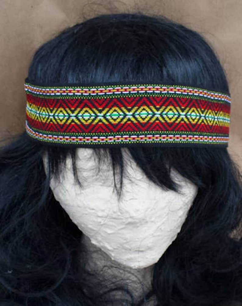 May include: A black headband with a colorful geometric pattern in red, yellow, green, and white. The headband is made of woven fabric and has a black backing.
