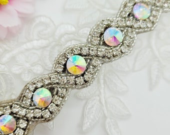 May include: Silver trim with iridescent rhinestones in a wavy pattern. The trim is perfect for adding a touch of sparkle to any project.