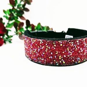 May include: A red jeweled dog collar with a black adjustable buckle. The collar is covered in small red crystals.