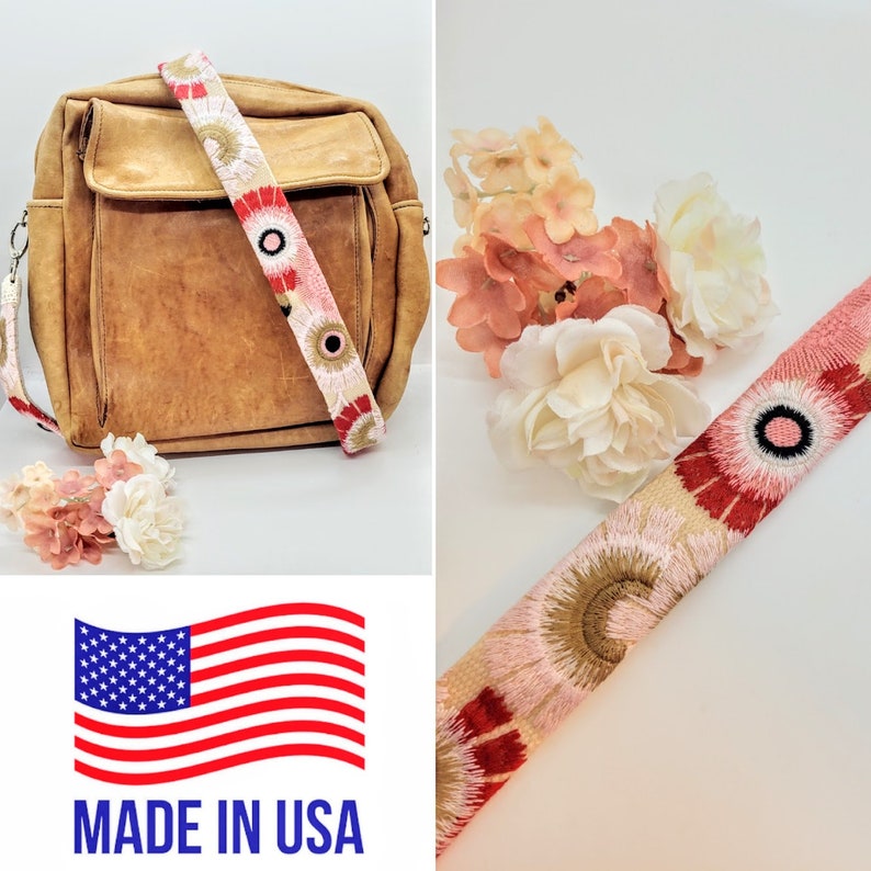 May include: A brown leather shoulder bag with a pink and red floral embroidered strap. The strap has a black circle with a pink center. The bag is on a white surface. The strap is also shown separately on a white surface with pink flowers. The image also includes a US flag with the text "MADE IN USA".