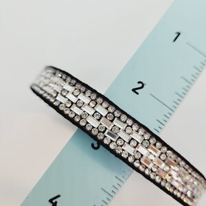 May include: A black ribbon with rows of clear rhinestones, measuring approximately 3 inches long.