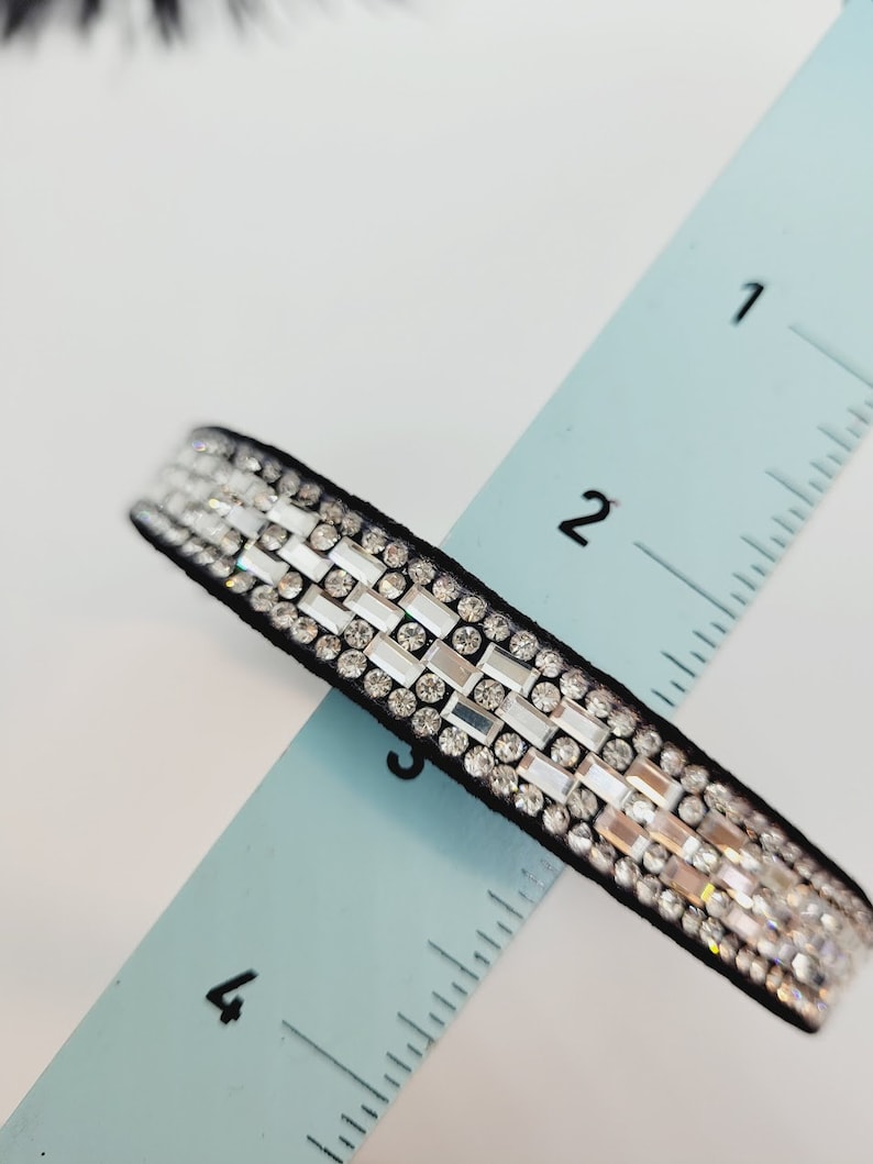 May include: A black ribbon with rows of clear rhinestones, measuring approximately 3 inches long.