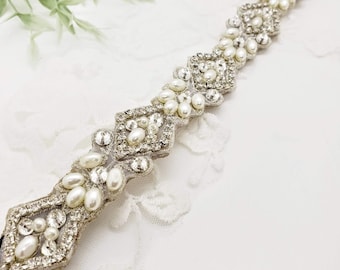 Peut inclure: Un serre-tête argenté et blanc perlé avec un motif géométrique. Le serre-tête est composé de petites perles et de strass.