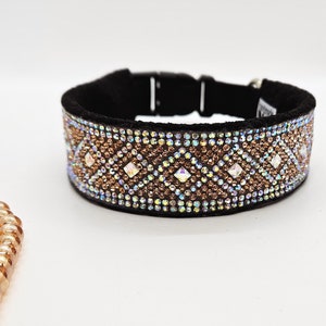 Puede incluir: Un collar de perro negro con un dise&ntilde;o de cristal marr&oacute;n e iridiscente. El collar tiene un patr&oacute;n de diamante con cristales m&aacute;s grandes en el centro de cada diamante.
