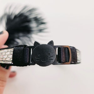 May include: Black cat-shaped breakaway buckle for a cat collar with a black and silver sparkly ribbon.