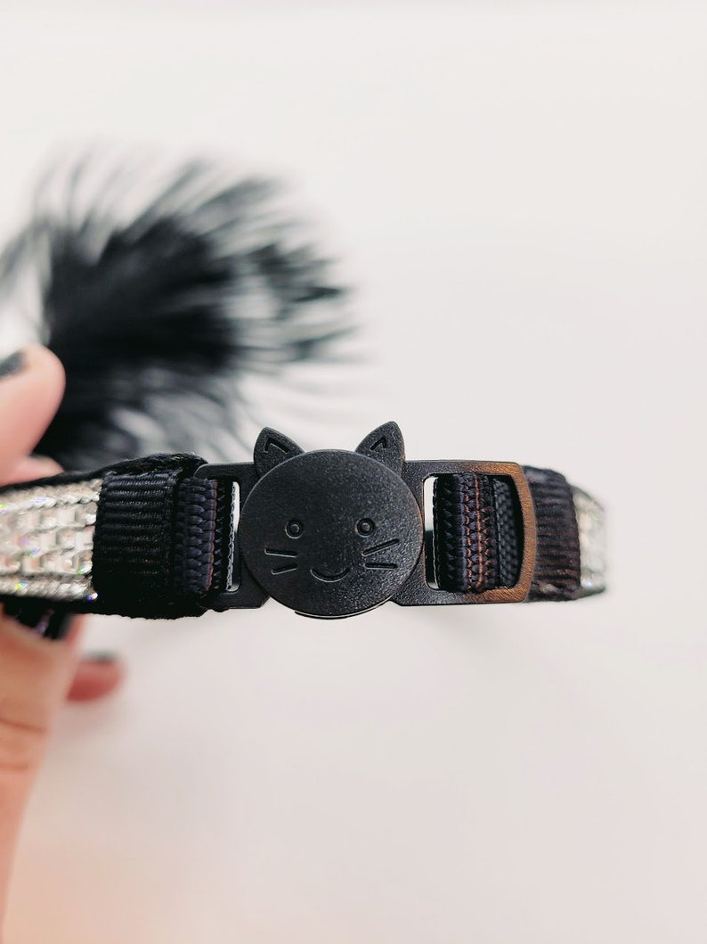 May include: Black cat-shaped breakaway buckle for a cat collar with a black and silver sparkly ribbon.
