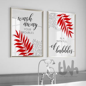 May include: Two framed wall art prints with silver frames. One print says "wash away your troubles" and the other says "in a bath full of bubbles". Both prints feature red leaf designs and gray floral accents.