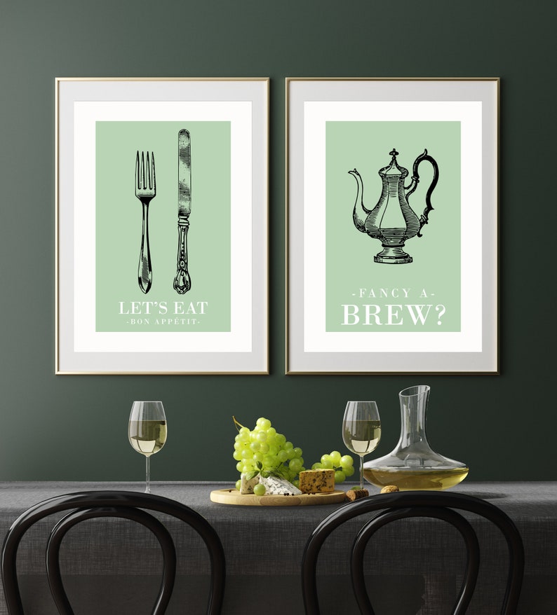 May include: Two framed prints with green backgrounds. The left print features a fork and knife with the text "Let's Eat - Bon Appetit." The right print features a teapot with the text "Fancy a Brew?"