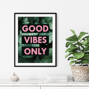 May include: A black framed print with a green tropical leaf background and the text "GOOD VIBES ONLY" in pink letters.