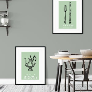 May include: Two framed prints with a green background and black illustrations. The top print features a fork and knife with the text "Let's Eat - Bon Appetit". The bottom print features a teapot with the text "Fancy a Brew?"