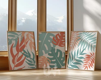 May include: Three framed prints with abstract tropical leaf designs in shades of teal, coral, and white. The prints are arranged in a row on a wooden floor.