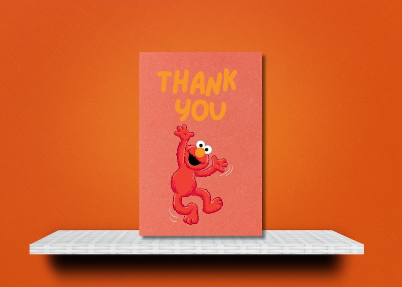 K&ouml;nnte beinhalten: Eine korallenfarbene Gru&szlig;karte mit den Worten &bdquo;THANK YOU&ldquo; in Gelb. Die Karte zeigt eine rote Cartoonfigur mit wei&szlig;en Augen und einem l&auml;chelnden Gesichtsausdruck in einer Tanzpose. Die Karte befindet sich auf einem wei&szlig;en Regal vor einem orangefarbenen Hintergrund.