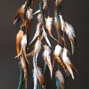 May include: Set of six feather hair extensions with brown, white, and teal feathers. Each extension has a brown string with a small wooden bead and a black clip.