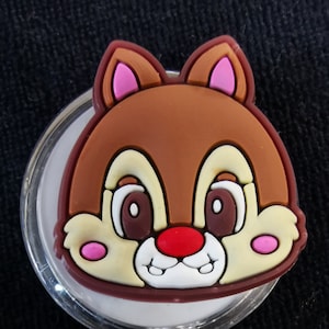 Könnte beinhalten: Ein durchsichtiger, ausziehbare Badgehalter aus Plastik mit einem braunen, gelben und rosafarbenen Comic-Chipmunk-Gesicht. Der Chipmunk hat eine rote Nase und weiße Zähne.