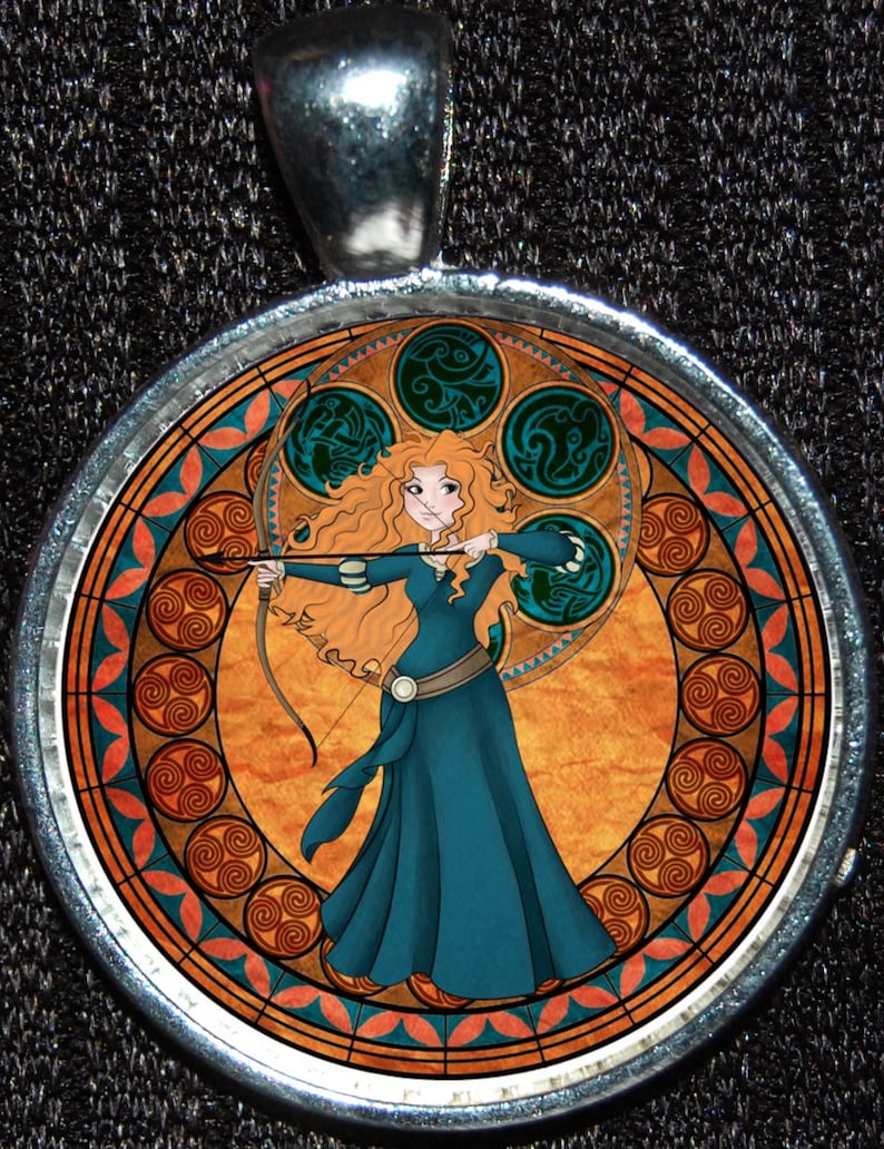 May include: A round silver pendant with a colorful stained glass design featuring a princess with long red hair holding a bow and arrow. The design is surrounded by a circular border of orange, blue, and green.
