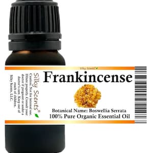 Puede incluir: Una botella de vidrio ámbar oscuro con una tapa negra, etiquetada como "Frankincense". La etiqueta incluye el nombre botánico Boswellia Serrata e indica que es aceite esencial orgánico puro 100%. La etiqueta también incluye una advertencia y el logotipo de Silky Scents.