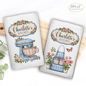 May include: Two white waffle-textured kitchen towels featuring the text Charlotte's Kitchen. One towel displays a blue stand mixer with a pink bowl and floral accents. The other towel shows a blue plaid apron, potted flowers, and a butterfly.