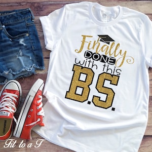 May include: White t-shirt with gold glitter text that reads "Finally done with this BS."  The text is in a black outline and includes a graduation cap graphic.