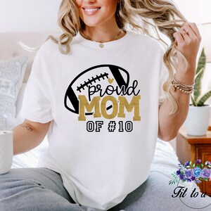 A white t-shirt with a football graphic and the words "proud MOM".  May be customized with your favorite player's number.