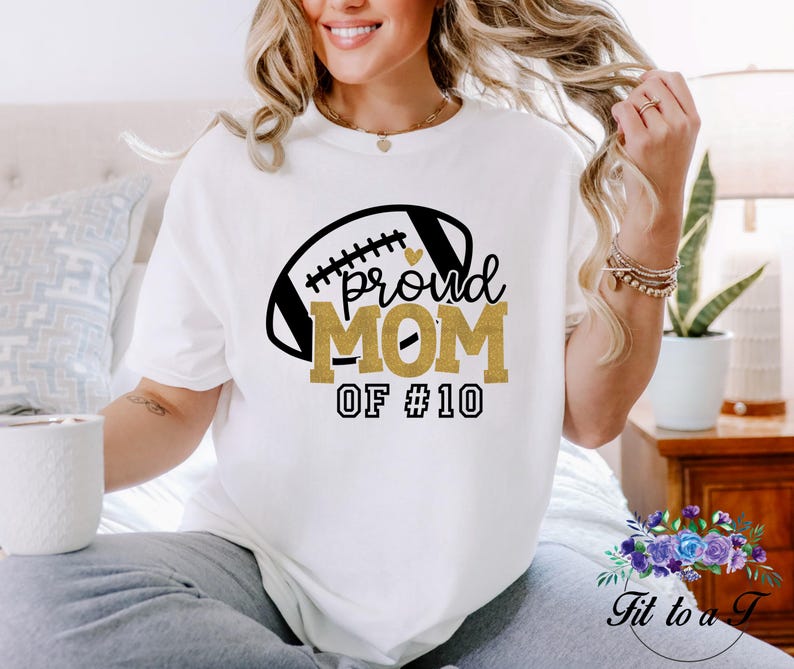 A white t-shirt with a football graphic and the words "proud MOM".  May be customized with your favorite player's number.