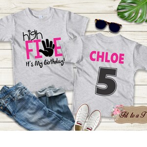 May include: Two gray t-shirts with pink and black text. The front shirt says "high FIVE" with a pink handprint and "It's My Birthday!" The back shirt says "CHLOE" in pink and has a black number "5" on it.