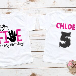 May include: White t-shirt with pink text that says "high FIVE" with a black handprint and "It's My Birthday!"  The back of the shirt has the name "CHLOE" in pink text and the number "5" in black.