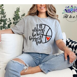 Gildan unisex basketball mom T-shirt featuring a basketball and heart graphic with the message “I’ll always be his biggest fan.”